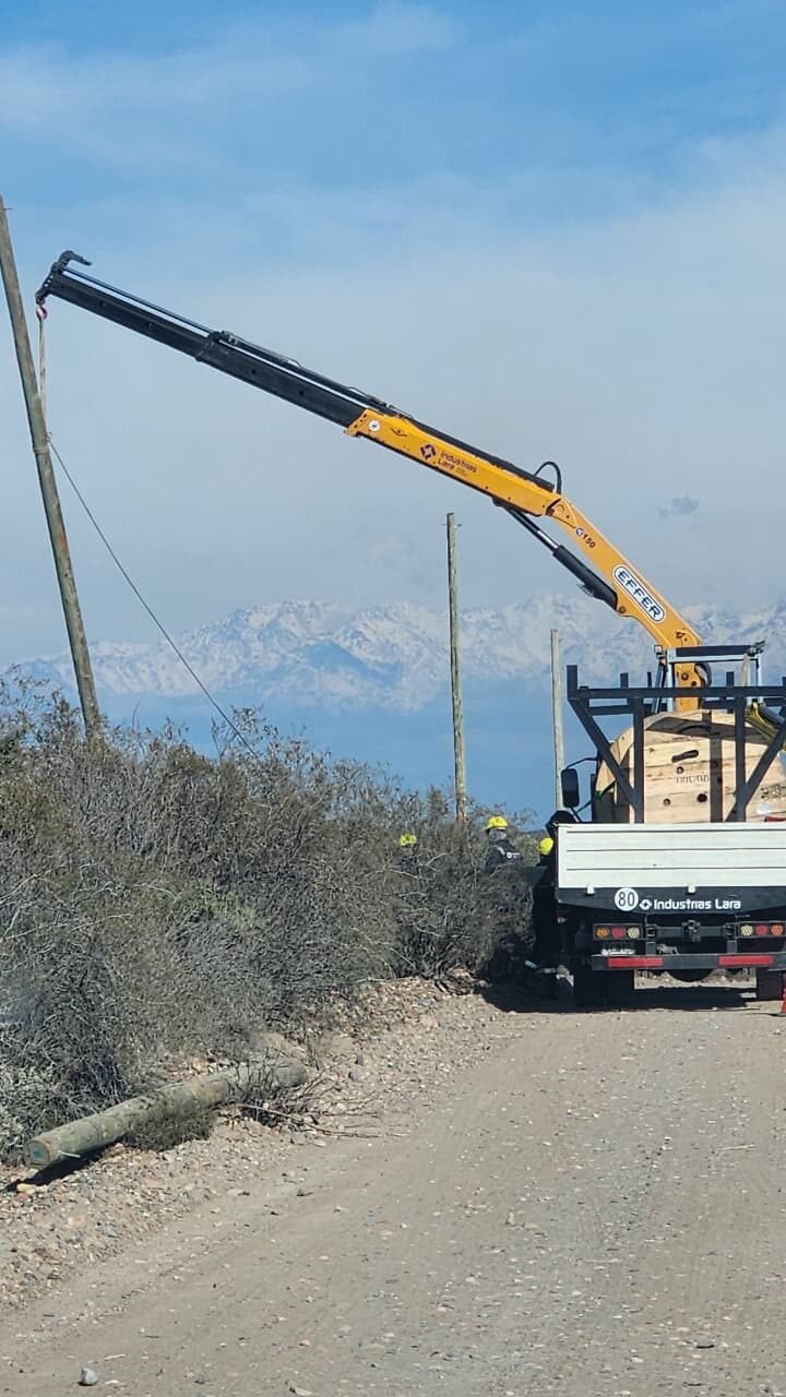 Camión grúa izando poste en zona rural