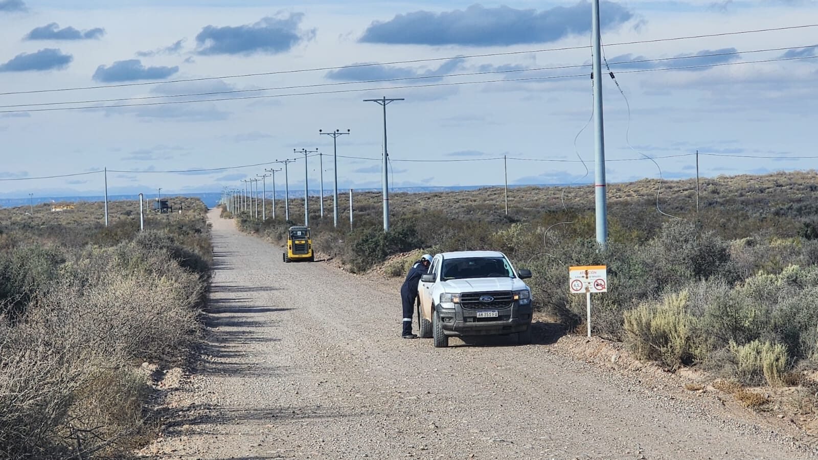 Línea de postes eléctricos en camino rural
